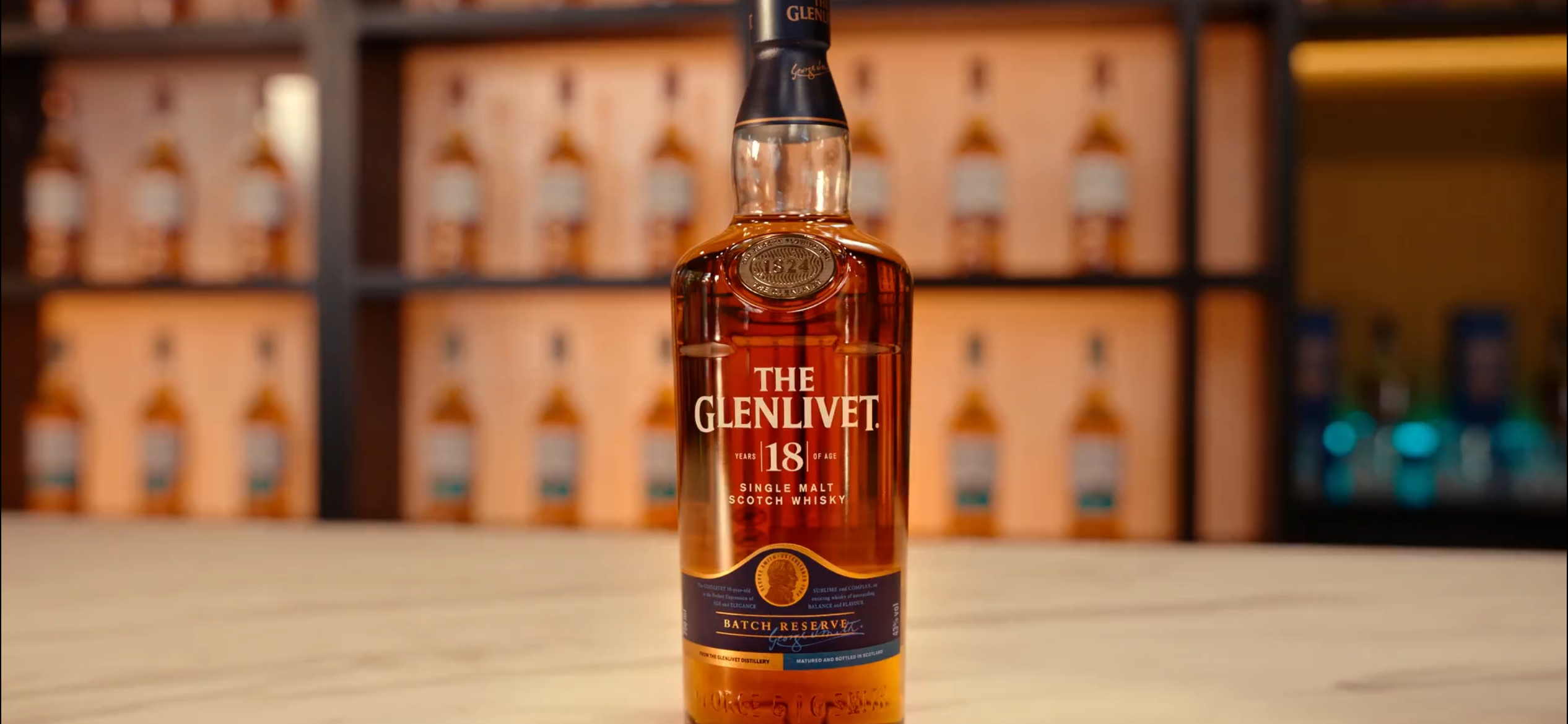 Close-up of The Glenlivet 18 Year Old Batch Reserve bottle in front of a glowing back bar