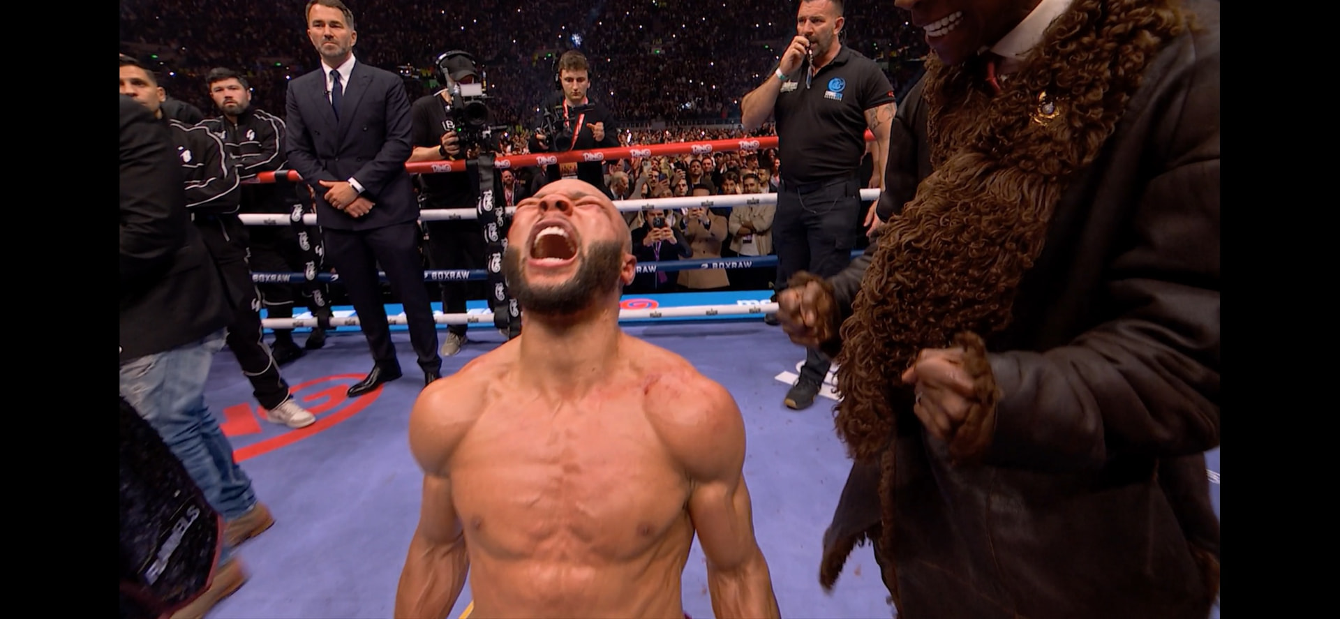 Boxer roaring in celebration inside the ring at a packed stadium boxing event