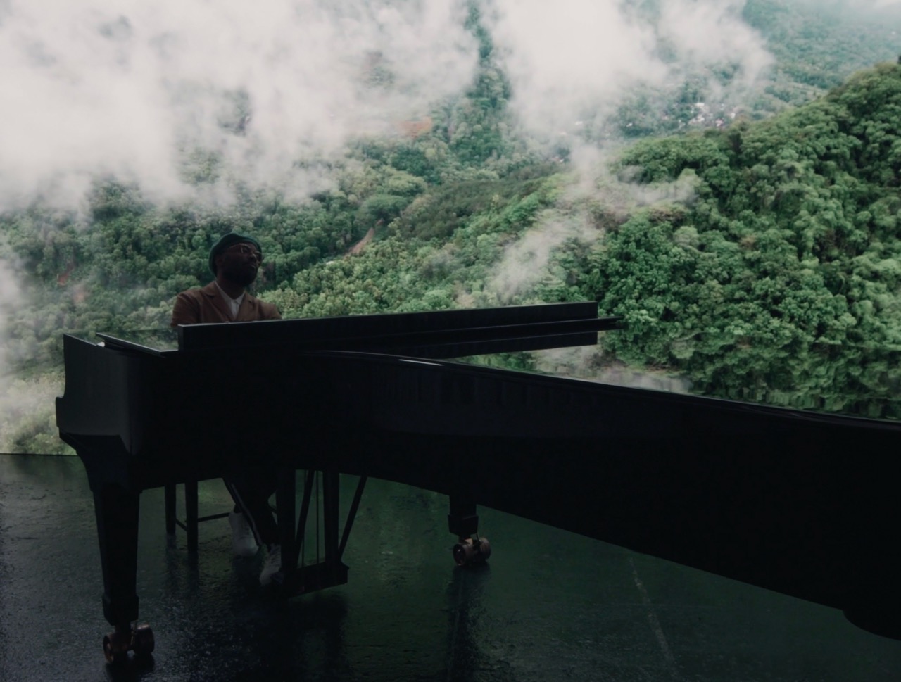 Musician playing a piano outdoors in misty mountain woodland